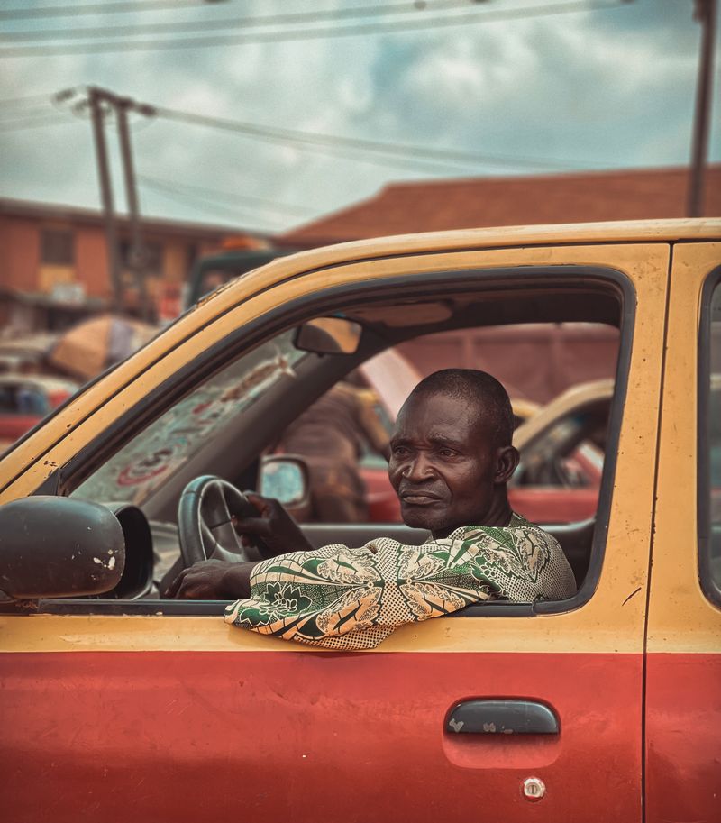 An older man at the wheel, looking out of his car window